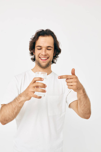hombre guapo vaso de agua en sus manos emociones posando fondo beige - Foto, imagen