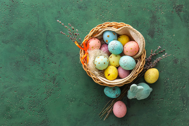 Cesta con huevos de Pascua pintados, lavanda y conejo sobre fondo verde - Foto, imagen
