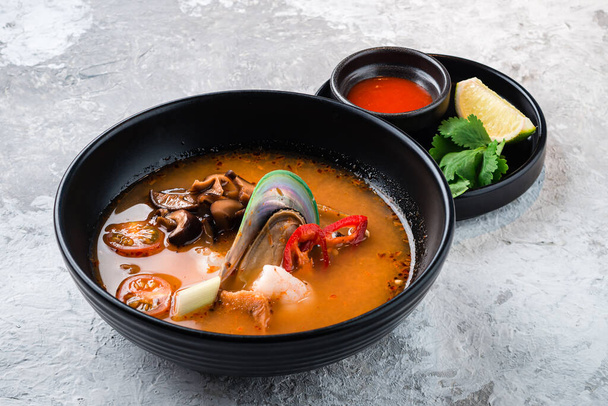klassinen Tom Yam Thaimaa ruokalaji. Perinteinen mausteinen Thai keitto Tom Yum katkarapuja ja äyriäisiä keraaminen kulho kivi tausta - Valokuva, kuva