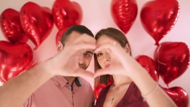 Happy beautiful young woman and handsome man making heart shape hand gesture - Footage, Video