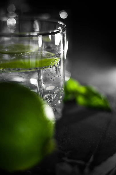 Vista de cerca de un vaso de agua cristalina con rodaja de fruta de lima - Foto, imagen