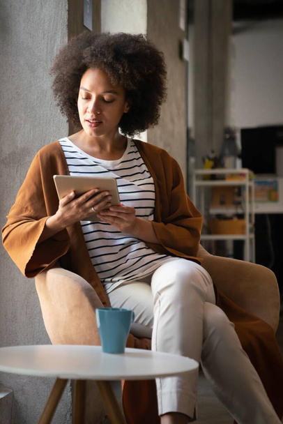 Enjoying coffee break with tablet. Successful black business woman working on digital tablet - Fotó, kép
