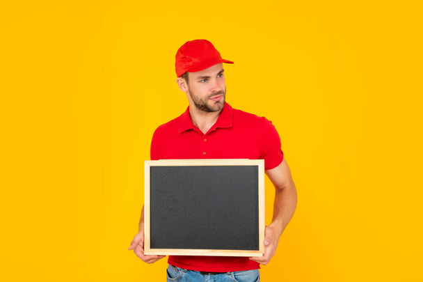 unshaven young man in red shirt hold blackboard with copy space on yellow background, announcement - Foto, Bild