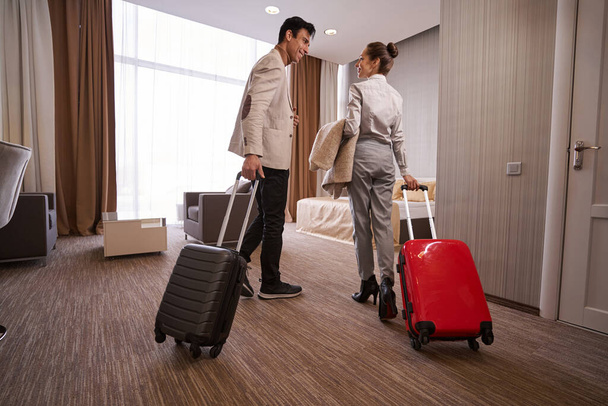 Pleased man and his companion with baggage in hotel room - Foto, immagini