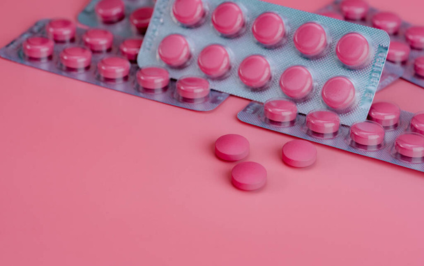 Vaaleanpunaiset tabletit ja läpipainopakkaus pillereitä vaaleanpunaisella taustalla. Reseptilääke. Vitamiinit, kivennäisaineet, ja täydentää käsite. Lääketeollisuus. Terveydenhuolto ja lääketiede. Farmaseuttinen tuote. - Valokuva, kuva