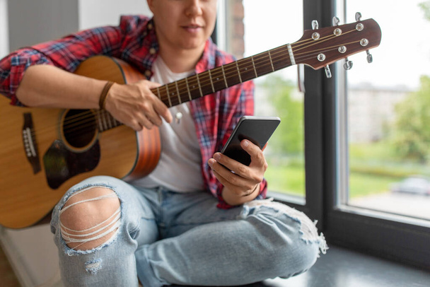 man with guitar and phone sitting on sill - Photo, Image