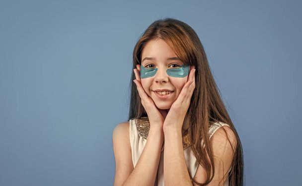 concept of natural beauty. healthy and tender skin. problem skin in adolescents. teen girl use eye patch. happy child with facial mask. korean cosmetics. cheerful kid with vitamin collagen patches - 写真・画像