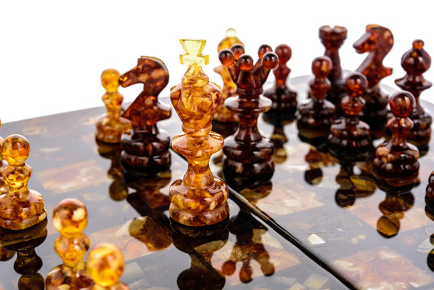 Naturalne bursztynowe figury szachowe stojące na powierzchni lakieru - Zdjęcie, obraz