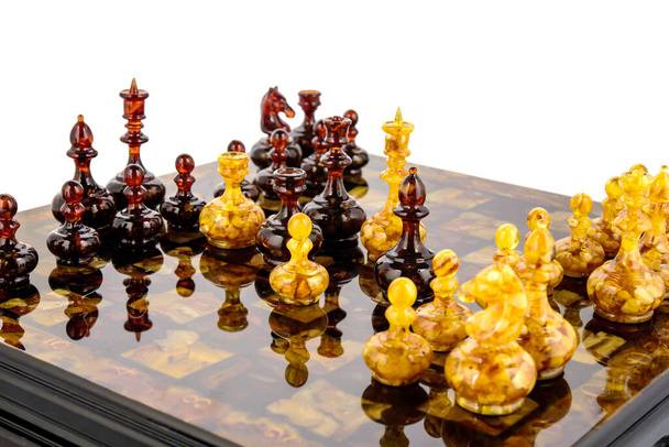 Lakquer yüzey tahtasında duran doğal kehribar farklı satranç taşları - Fotoğraf, Görsel