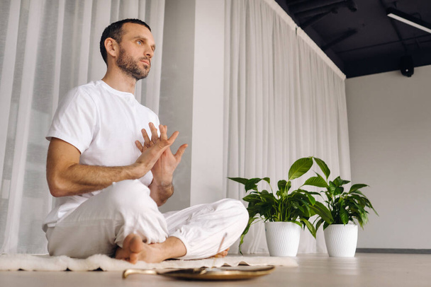 Close-up of a man in white sportswear doing yoga in a fitness room with a balgovon. the concept of a healthy lifestyle. - Valokuva, kuva