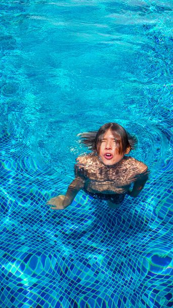 Portrait of a boy in the outdoor swimming pool. Teenager in the swimming pool. Summer vacation at the hotel or outdoor swimming lessons. Healthy lifestyle concept - Photo, image