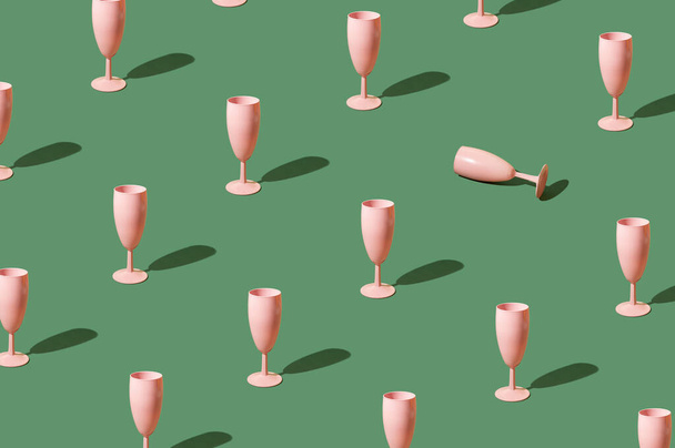 Patrón hecho de copas de champán rosa sobre un fondo verde. Celebración fiesta concepto estético - Foto, imagen