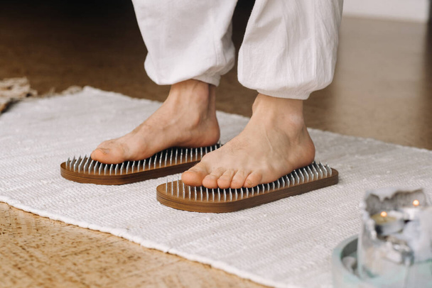 The man's feet are next to boards with nails. Yoga classes. - 写真・画像