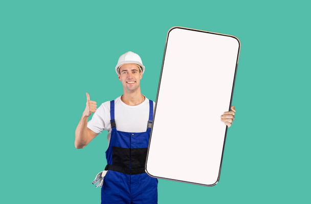 Bauarbeiter mit Helm zeigt großen Handybildschirm - Foto, Bild