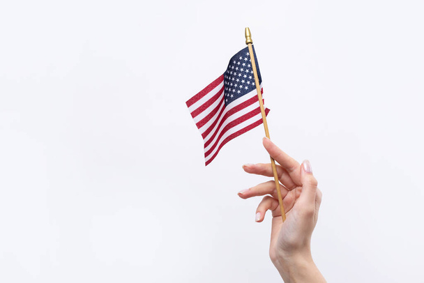 A beautiful female hand holds an American flag on a white background. - Fotoğraf, Görsel