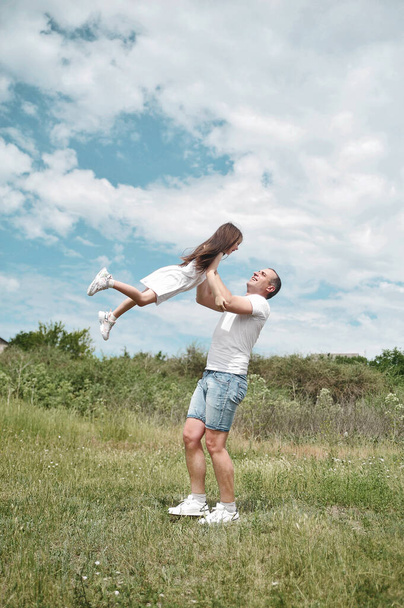 Dad and daughter have fun in the field . Happy family concept. Dad throws his daughter into the sky  - Valokuva, kuva
