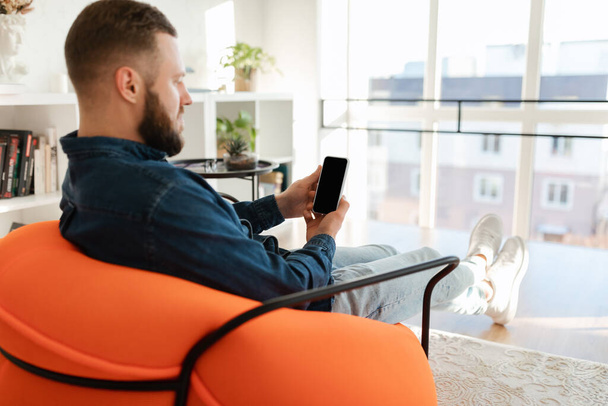 Man Using Phone With Empty Screen Sitting In Chair Indoors - Photo, Image