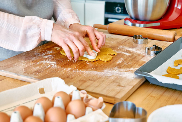 Женские руки вырезают печенье в форме сердца на столе на кухне. Домашняя выпечка или торт. Пекарные печенья. - Фото, изображение
