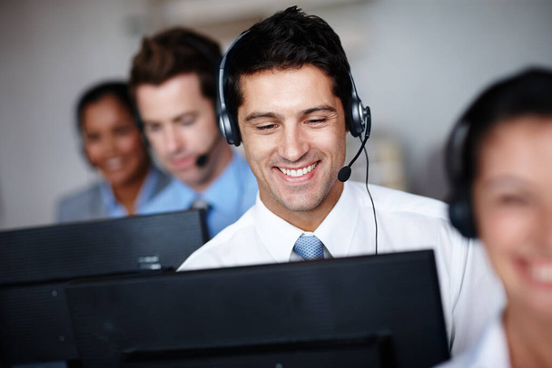 Pleased to assist you. A handsome young call center agent enjoying his job tremendously. - Photo, Image