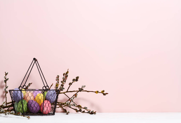 Arrangement of basket with multi colored eggs and willow branches  - Foto, Imagen
