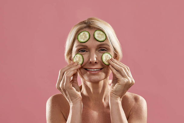 Portrait of woman apply cucumber slices on face - Фото, изображение
