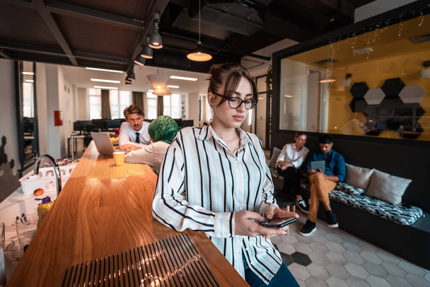 Businesswoman with glasses using mobile phone at modern startup open plan office interior. Selective focus  - Fotó, kép