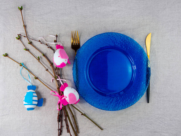 Ostern Tischdekoration leere blaue Glasplatte Gabelmesser mit Baumzweigen auf Leinentuch Draufsicht. Festlich Menü Gericht Ort Natürliche Baumwollkerne Stil Geschirr minimale Wohnkultur Landschaft ästhetisch - Foto, Bild