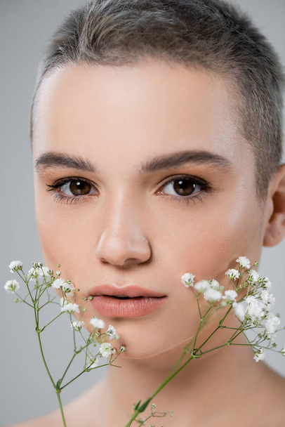 close up view of woman with perfect skin and natural makeup near gypsophila flowers isolated on grey - Photo, image