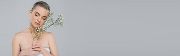 giovane donna ad occhi chiusi in posa con piccoli fiori bianchi isolati su grigio, striscione - Foto, immagini