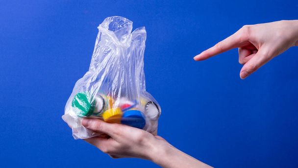 Die Hand einer Frau hält eine Tasche mit Plastikdeckeln zum Recyceln - Foto, Bild