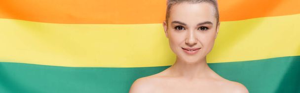 woman with naked shoulders smiling at camera near lgbt flag on background, banner - Photo, Image