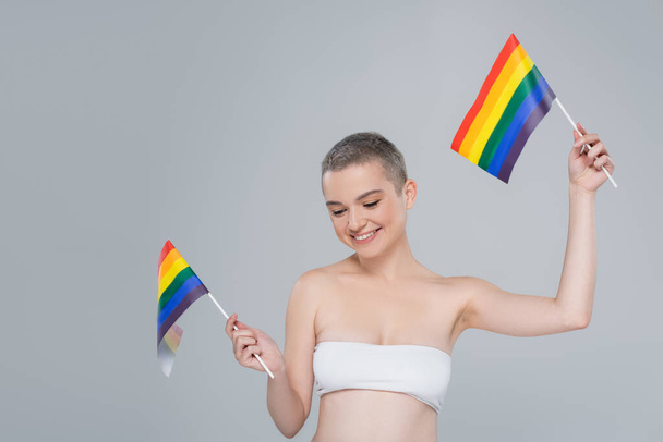 happy woman in white top posing with small lgbt flags isolated on grey - Fotografie, Obrázek