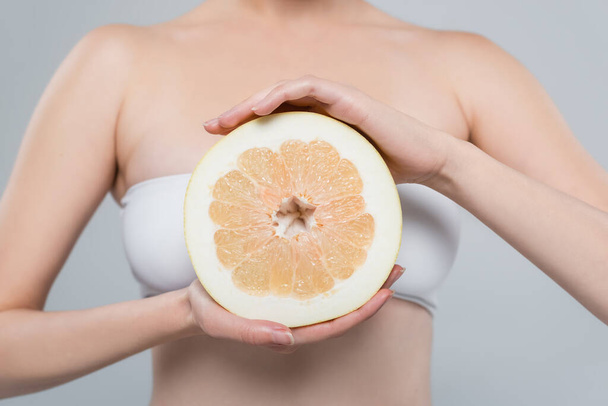 cropped view of woman with half of ripe grapefruit isolated on grey - Photo, image