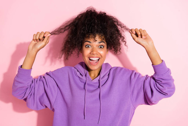 Photo of impressed shiny afro girl wear violet sweatshirt holding hands arms hair curls smiling isolated pink color background - Valokuva, kuva