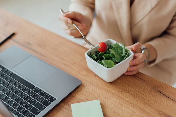 Woman eat healthy green food in the office near notebook - Fotó, kép