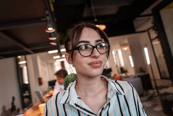 Portrait of businesswoman in casual clothes with glasses at modern startup open plan office interior. Selective focus  - Fotó, kép