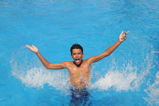 Boy teenager splashing water open arms pool - Fotó, kép
