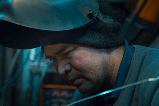 Portrait of an argon arc welder with a helmet on his head at the workplace - Photo, Image