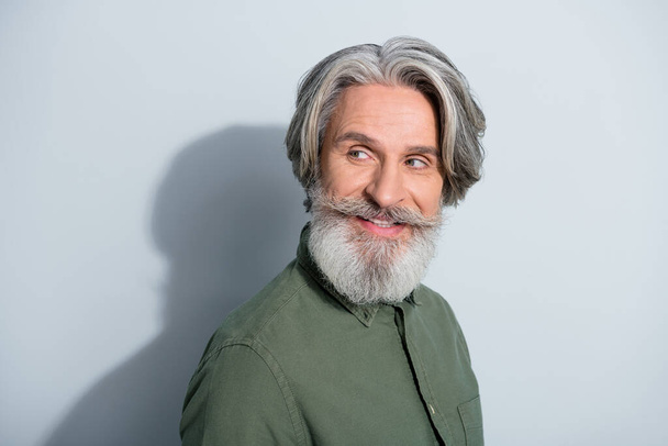 Portrait of attractive cheerful curious grey-haired man copy empty space looking aside isolated over gray pastel color background - Valokuva, kuva