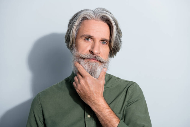 Portrait of attractive well-groomed successful grey-haired man touching beard deciding isolated over gray pastel color background - Foto, immagini