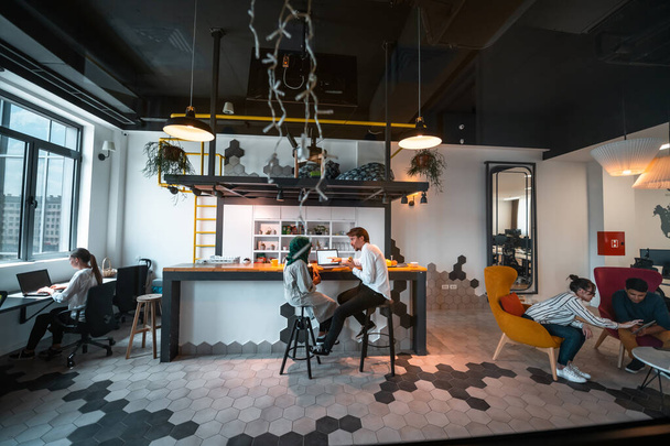 Group of casual multiethnic business people taking break from the work doing different things while enjoying free time in relaxation area at modern open plan startup office - Fotoğraf, Görsel