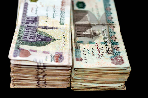 Stacks of obverse sides of 200 LE and 100 LE Egyptian pounds banknotes, two hundred pounds has an image of Mosque of Qani-Bay and one hundred pounds has image of Sultan Hassan Mosque Isolated on black - Фото, зображення