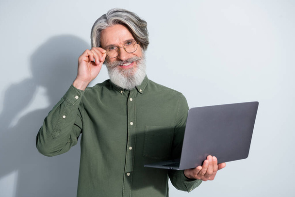 Portrait of handsome trendy cheerful grey-haired man using laptop e-commerce touching specs isolated over gray pastel color background - Φωτογραφία, εικόνα