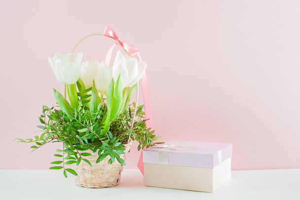 A bouquet of white tulips and a gift box on a pink background. - Photo, image