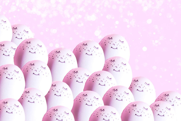 Osterferienkonzept mit niedlichem, handgemachtem Ei. Eier mit lustig bemalten Gesichtern auf rosa Hintergrund mit Neonlicht und Unschärfe - Foto, Bild