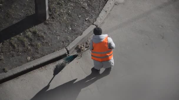 A woman janitor in a special suit sweeps the street with a broom - Footage, Video