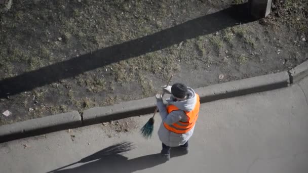 A woman janitor in a special suit sweeps the street with a broom - Footage, Video