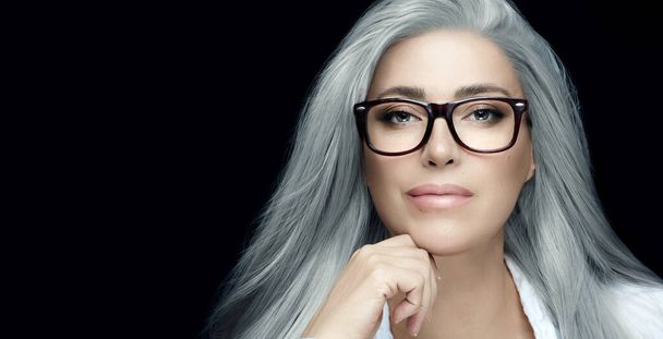 Damenbrillen. Stilvolle Silberhaar-Frau mit klarer Brille, die selbstbewusst in die Kamera starrt. Brillenbanner isoliert auf schwarz mit Kopierraum - Foto, Bild