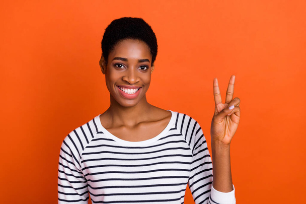 Portrait of attractive cheerful funky girl showing v-sign isolated over vibrant orange color background - Фото, изображение