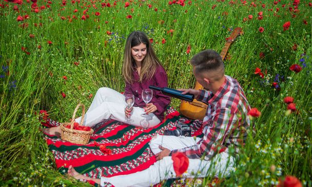 Feeling of love. happy relations. girl and guy in field. romantic couple drink wine in poppy flowers on date. family summer vacation. happy man and woman in love enjoy spring weather - Photo, Image